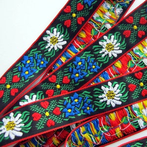 jacquard trim with white edelweiss flowers, blue flowers, green leaves and four red hearts, on black with red woven edges, bavarian trim