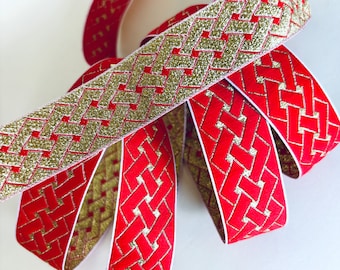 May include: Red and gold ribbon with a woven pattern. The ribbon is folded and twisted, showing the pattern from different angles.