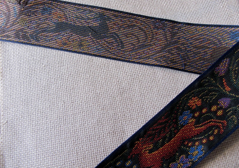 Medieval tapestry wide Jacquard trim with a brown stag and a blue wolf in a floral garden on a black background with back of trim shown