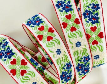 EDELWEISS & HEARTS Jacquard trim White edelweiss, blue, red, green on white. Sold by the yard. 1 inch wide. V2773-E Bavarian trim