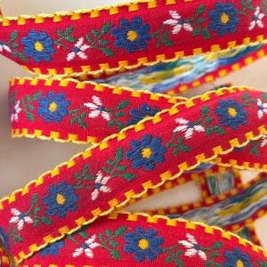 BAVARIAN DAISIES Jacquard trim. Blue, white, green, yellow on red with yellow edges. Sold by the yard. 3/4 inch wide. 3799-A. Scandinavian