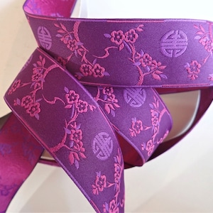 May include: Purple ribbon with a pink floral and Chinese symbol design.