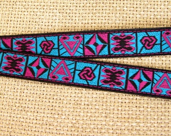 May include: Black, pink, and blue patterned ribbon with geometric designs. The ribbon is woven with a repeating pattern of triangles, swirls, and diamonds.