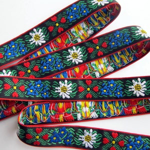 jacquard trim with white edelweiss flowers, blue flowers, green leaves and four red hearts, on black with red woven edges, bavarian trim