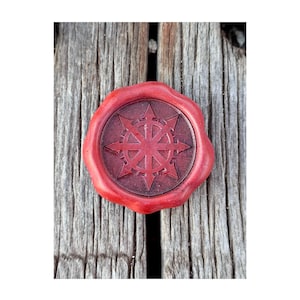 Peut inclure: Un sceau de cire rouge avec un emblème détaillé rouge foncé au centre. Le sceau est circulaire avec un bord texturé, posé sur une surface en bois vieilli. L'emblème présente un motif en forme d'étoile.
