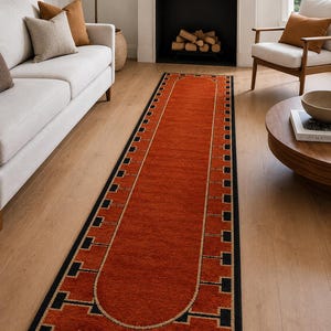 Puede incluir: Una alfombra de pasillo larga y rectangular con un centro de color naranja quemado sólido y un diseño de extremo redondeado. El borde consiste en un patrón geométrico negro con formas cuadradas repetitivas y líneas finas que enmarcan.