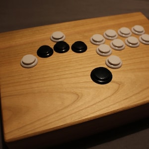 May include: A wooden arcade button panel with black and white buttons. The panel is made of light wood and has a smooth finish.