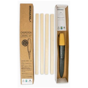 Op de afbeelding: Een Moraknil Chopstick Carving Kit, met een snijmes, berkenhouten stokjes en een beschermhoes. De kit wordt geleverd in een bruine kartonnen doos met productinformatie en een diagram van het snijmes.