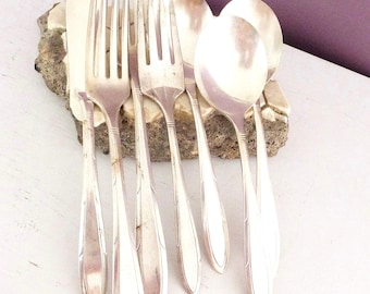 May include: A collection of vintage silverware, including forks, spoons, and a knife, arranged on a decorative stone. The silverware has a shiny, silver finish and a classic design, perfect for a formal dining setting.