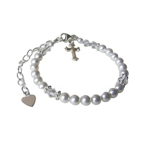 May include: A silver bracelet with white pearls, a small silver cross charm, and a silver heart charm.