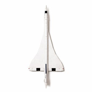 May include: A white model Concorde supersonic jet, seen from above. The model has a long, thin fuselage, delta wings, and a pointed nose. Black and red details are on the wings and tail. The model is set against a white background.