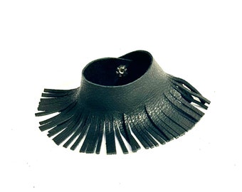 Könnte beinhalten: Ein schwarzes Lederarmband mit Fransen. Das Armband ist aus weichem, geschmeidigem Leder gefertigt und hat ein schlichtes, elegantes Design.