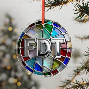 Può includere: Ornamento natalizio rotondo con un design a vetrata. L'ornamento presenta le lettere "FDT" in un carattere metallico argentato. Il vetro è multicolore con sfumature rosse, verdi, blu e gialle. Un nastro rosso è attaccato per appenderlo.