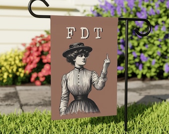 May include: A rectangular garden flag with a brown background featuring the text FDT in white letters above a black and white illustration of a person in a high-collared Victorian-style dress and hat, holding up their middle finger.
