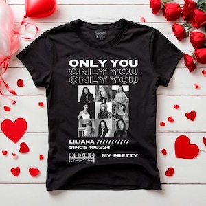 Op de afbeelding: Zwart T-shirt met witte tekst die drie keer "ONLY YOU" zegt. Onder de tekst is een collage van zwart-witfoto's van vrouwen. De tekst "LILIANA SINCE 100224" staat onder de collage. De tekst "MY PRETTY" staat onder de datum.