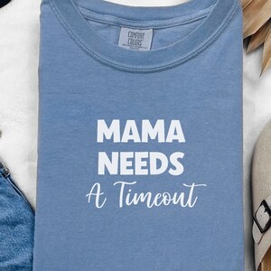 May include: A light blue t-shirt with the text "MAMA NEEDS A TIMEOUT" in white lettering.