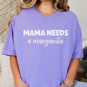 May include: A lavender t-shirt with the text "MAMA NEEDS a margarita" in white.