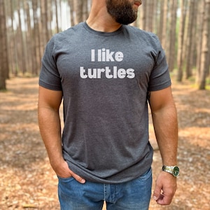 May include: A dark gray t-shirt with the text "I like turtles" printed in white.