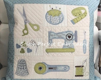 May include: Square decorative pillow with a light blue border and a patchwork design featuring sewing tools. The central panel displays a sewing machine, scissors, a pin cushion, a measuring tape, a thimble, a rotary cutter, and a spool of thread. The text "Stitch Perfect Embroidery" is also visible.