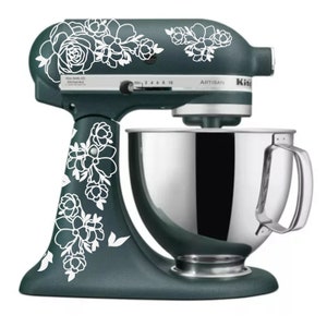 May include: A teal stand mixer with a silver bowl and white floral decals. The mixer has a control panel with the word "Artisan" and numbers 2, 4, 6, 8, and 10.