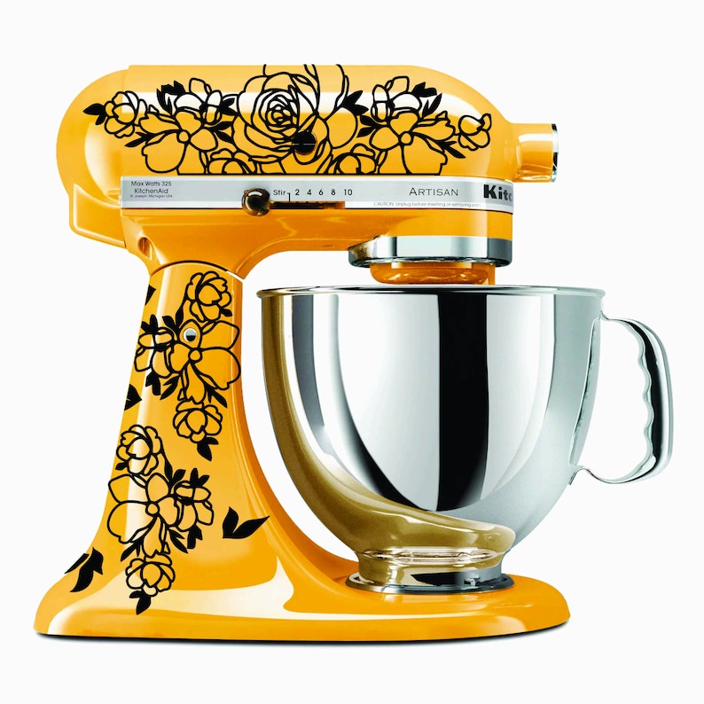 Puede incluir: Una batidora de pie amarilla con un dise&ntilde;o floral negro y un taz&oacute;n plateado. La batidora tiene un panel de control plateado con el texto "Artisan" y "Max Watts 325 KitchenAid".