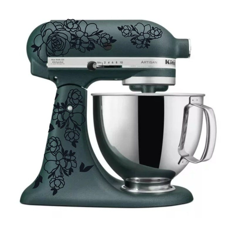 May include: A teal stand mixer with a silver bowl and black floral decals. The mixer has a control panel with numbers 2, 4, 6, 8, and 10. The text "Artisan" is printed on the mixer.