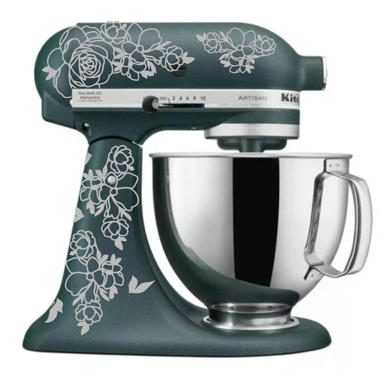 May include: A teal stand mixer with a silver bowl and a white floral design. The mixer has the word "Artisan" printed on the side.