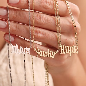 May include: Three gold necklaces with nameplates that read "Olive", "Rocky", and "Hope". The necklaces are on a silver chain and a gold chain.