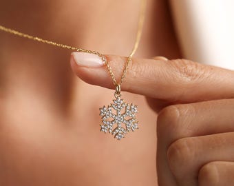 以下が含まれることがあります： 雪の結晶のペンダントが付いた金のチェーンネックレス。雪の結晶は透明なクリスタルでできています。