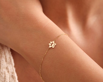 Puede incluir: Un brazalete de cadena dorada con un dije en forma de huella de pata que dice "Lexi".