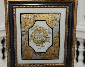May include: Framed artwork featuring the Pisces zodiac symbol. The gold-toned image of two fish is set against a white background, framed by gold and black borders. A small metal ring is attached at the top for hanging.