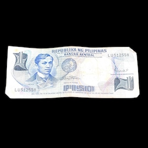 May include: A blue and white Philippine one peso banknote featuring a portrait of Jose Rizal, the national hero of the Philippines. The banknote has the text "Republika ng Pilipinas" and "Bangko Sentral" printed on it. The serial number "LU512558" is visible on the banknote.