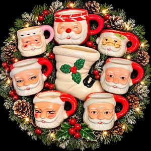 May include: A collection of six ceramic Santa Claus mugs surrounding a central white ceramic stocking planter with green holly leaves and red berries, all arranged on a circular wreath with pine needles, pinecones, and small warm white lights.