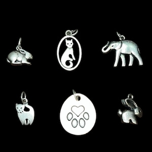 May include: Six silver charm pendants featuring a cat, elephant, rabbit, paw print, and two different rabbits. The charms are all silver and have a polished finish.