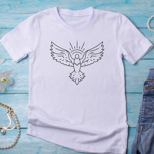以下が含まれることがあります： 白いTシャツに、黒い線で描かれた、羽を広げた鳩と、その上に輝く太陽のイラストが描かれています。