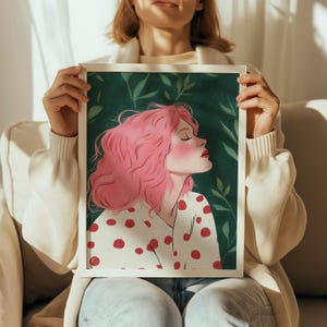 May include: A framed illustration of a woman with pink hair wearing a white shirt with red polka dots. The background is a green leafy pattern.