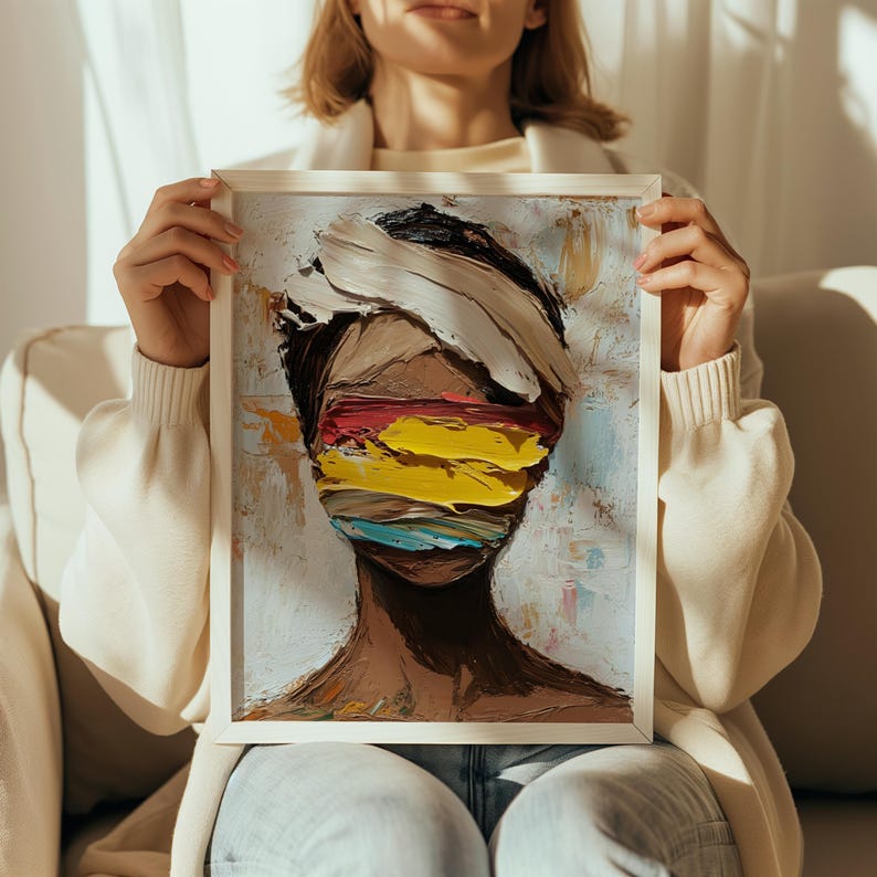 May include: A framed painting of a person's face with colorful abstract brushstrokes covering the eyes. The background is a light blue with hints of yellow and pink.