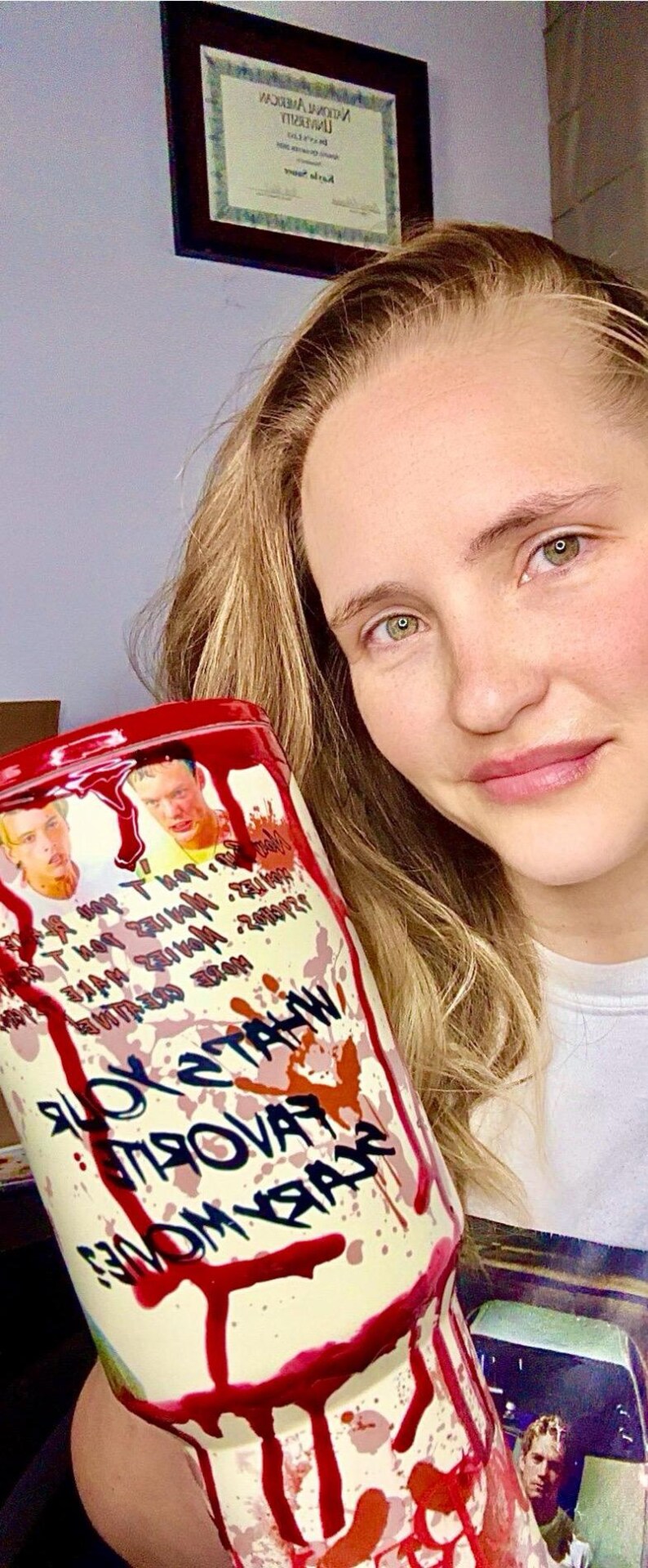 May include: A white and red stainless steel tumbler with a bloody handprint design and the text "You Satan" and "Pray For" on the side. The tumbler is held by a person with long blonde hair.