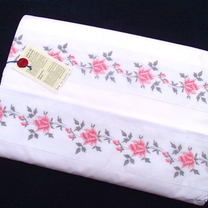 Puede incluir: Juego de sábanas de algodón blanco con un patrón bordado de rosas rosas. El juego de sábanas incluye una sábana plana y una sábana ajustable.