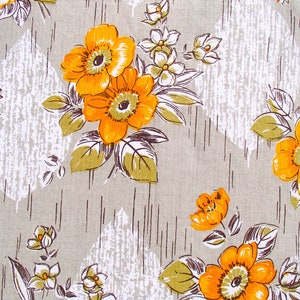 May include: A beige fabric with a repeating pattern of orange and white flowers. The flowers have a stylized design with a central yellow circle and white petals.