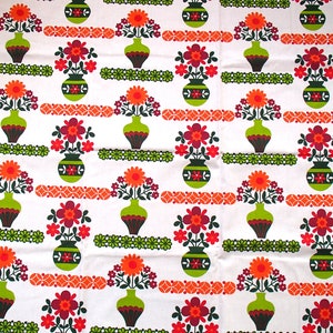 May include: White fabric with a repeating pattern of green vases filled with orange, red, and purple flowers. The vases have a brown and green striped pattern.