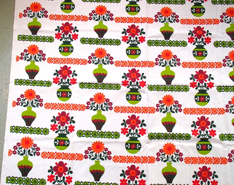 May include: White fabric with a repeating pattern of green vases filled with orange, red, and purple flowers. The vases have a brown and green striped pattern.