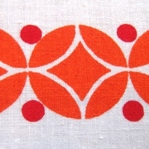 May include: Orange and red geometric pattern on a white fabric background. The pattern features a repeating design of overlapping circles and diamonds.
