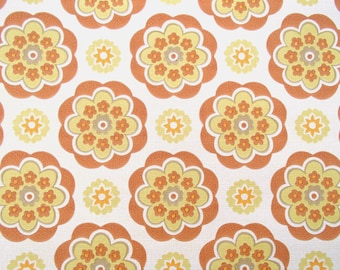 Puede incluir: Un patrón repetido de formas florales de color naranja, amarillo y marrón sobre un fondo blanco. El patrón recuerda al papel tapiz de los años 70.