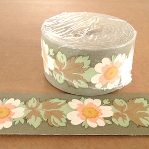 May include: A roll of green and white wallpaper border with a floral pattern. The border features pink flowers with yellow centers and brown leaves.