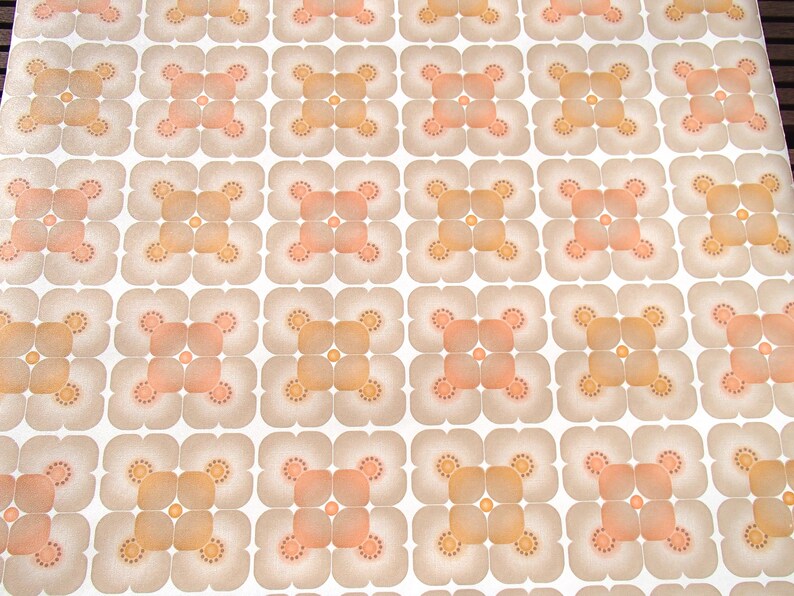 May include: A vintage wallpaper pattern with a repeating design of four-leaf clover shapes in shades of brown, orange, and peach on a white background.