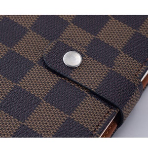 May include: Close-up of a brown and black checkered notebook cover with a silver button.