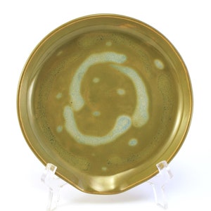 May include: A green ceramic dish with a light blue glaze. The dish has a rounded shape and a small pour spout.