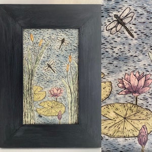 May include: A framed artwork depicting a nature scene with water lilies, dragonflies, and cattails. The artwork is painted in shades of green, pink, yellow, and brown.