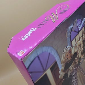 以下が含まれることがあります： Evening Majesty Barbie人形用の鮮やかなピンク色の長方形の段ボール箱。パッケージにはBarbieのロゴとEvening Majesty Dollの文字が記載されています。側面には小さな赤いMattelのロゴと番号17235が印刷されています。